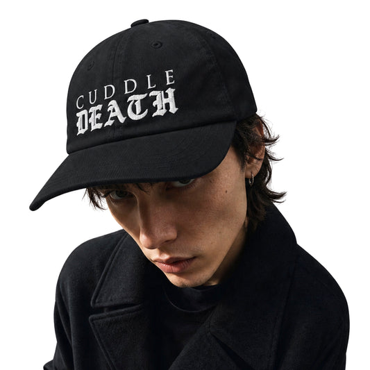 Model wearing black Cuddle Death dad hat with white gothic logo on a white background