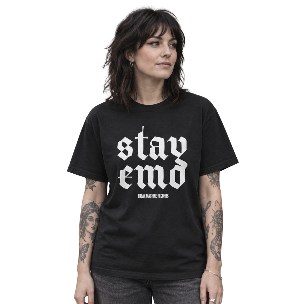 Model wearing the black Stay Emo T-shirt with white gothic lettering and charcoal jeans outside a record shop.